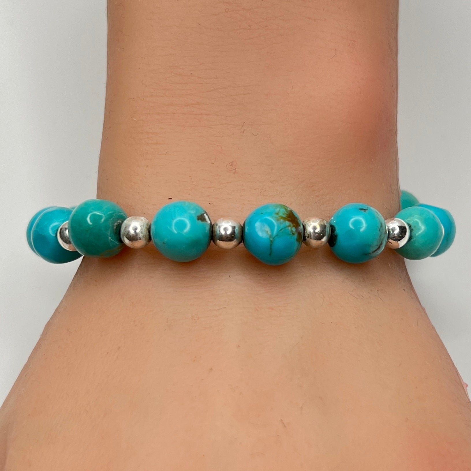 Turquoise and silver beaded bracelet worn on wrist – 9mm stones