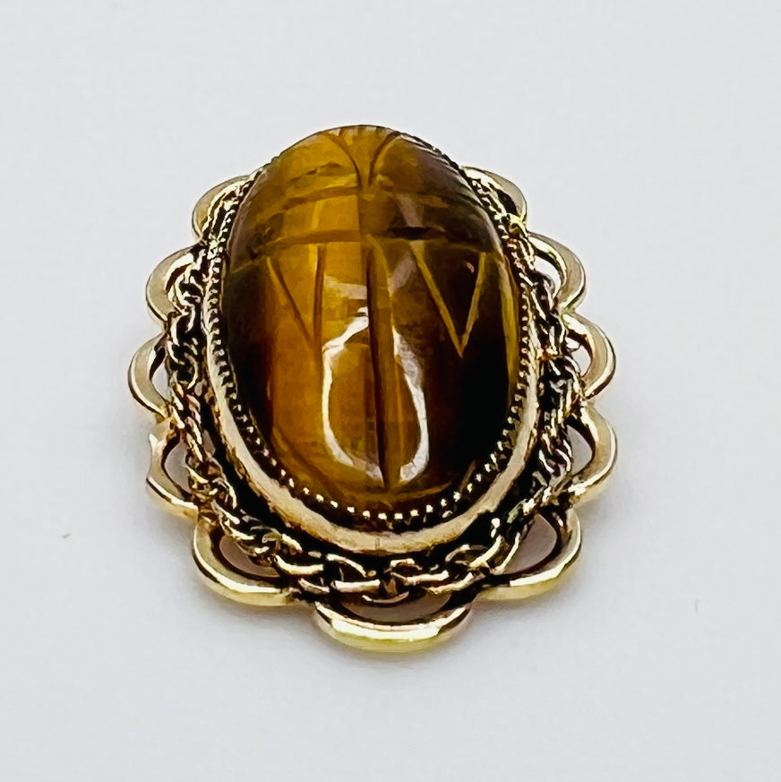 Side view of oval tiger’s eye brooch with high dome and scalloped gold setting