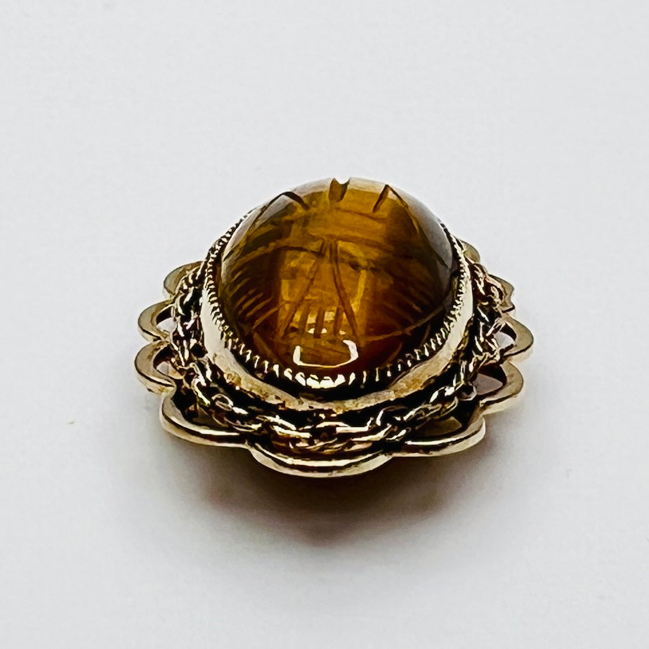 Side view of oval tiger’s eye brooch with high dome and scalloped gold setting