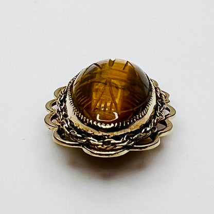 Side view of oval tiger’s eye brooch with high dome and scalloped gold setting
