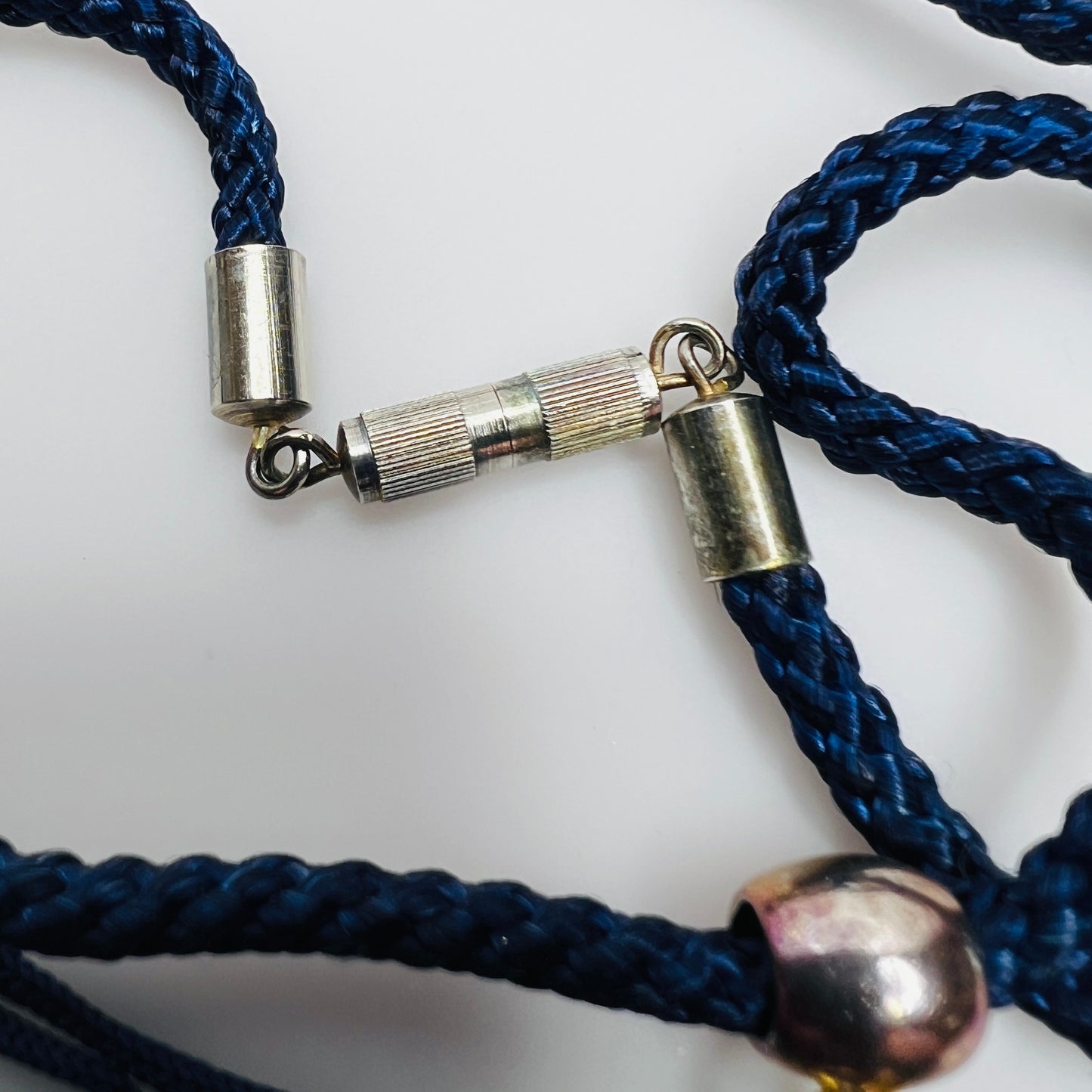 Silver-tone barrel clasp on navy fabric cord necklace