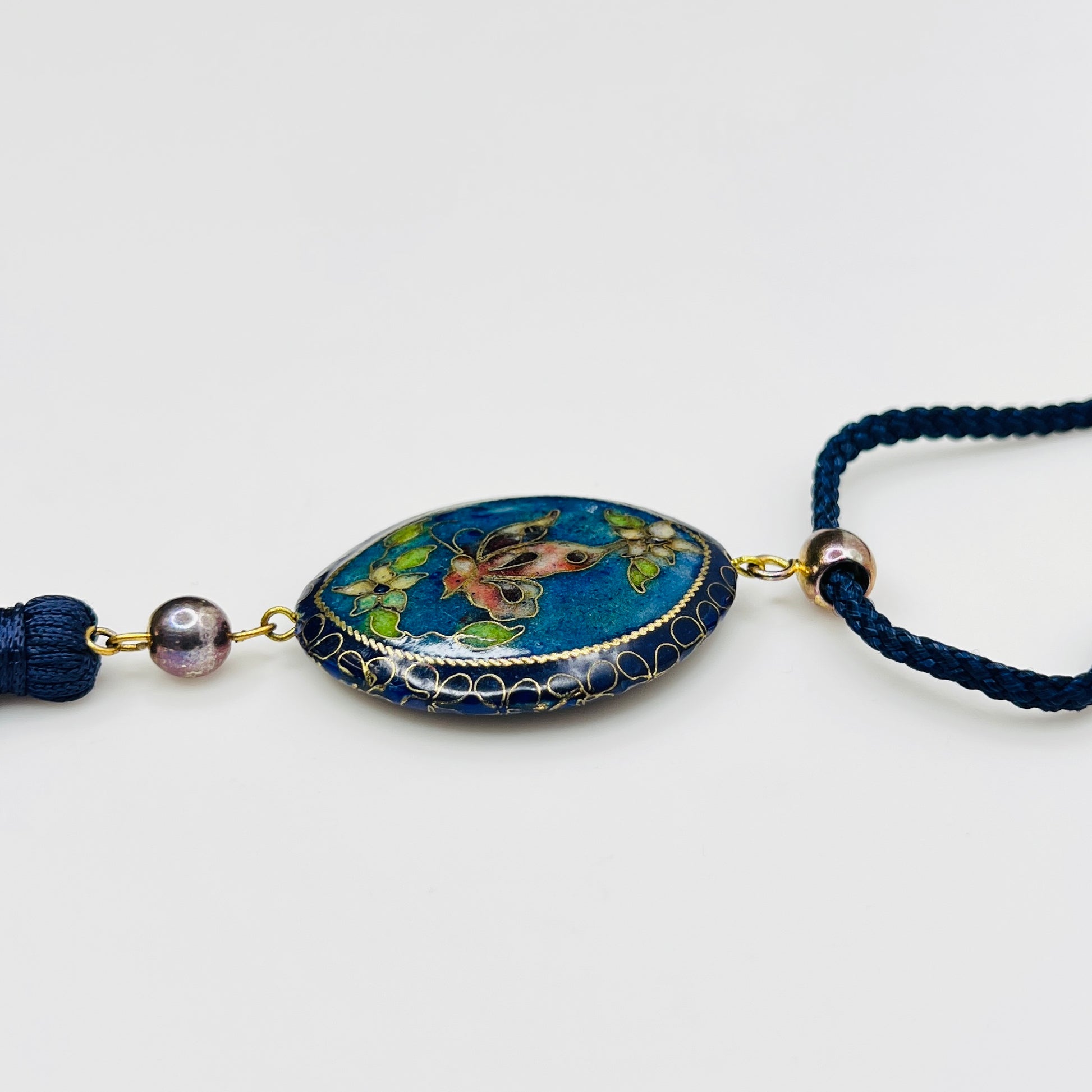 Close-up of butterfly cloisonné pendant with tassel drop
