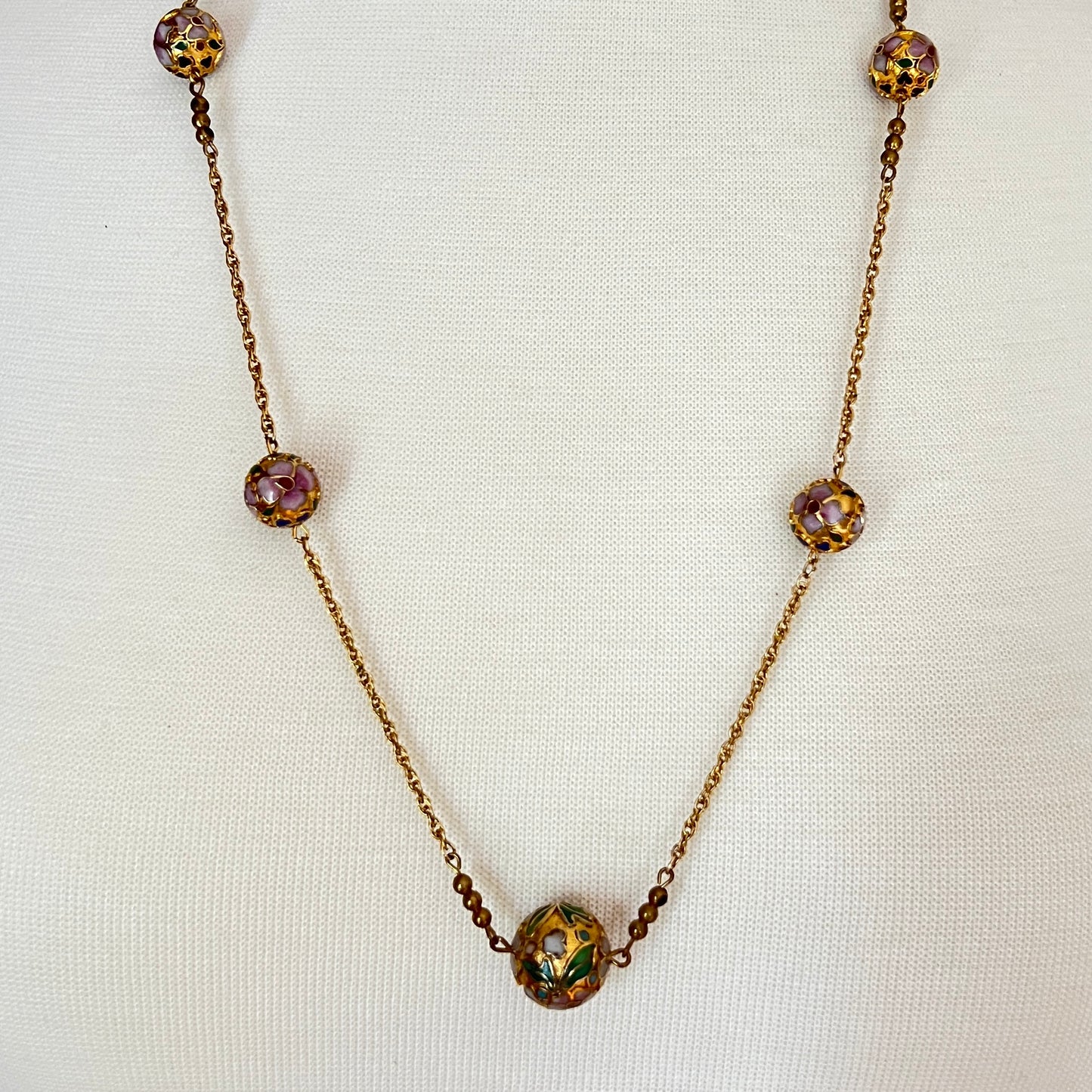 Close-up of necklace center bead with green and white floral detail