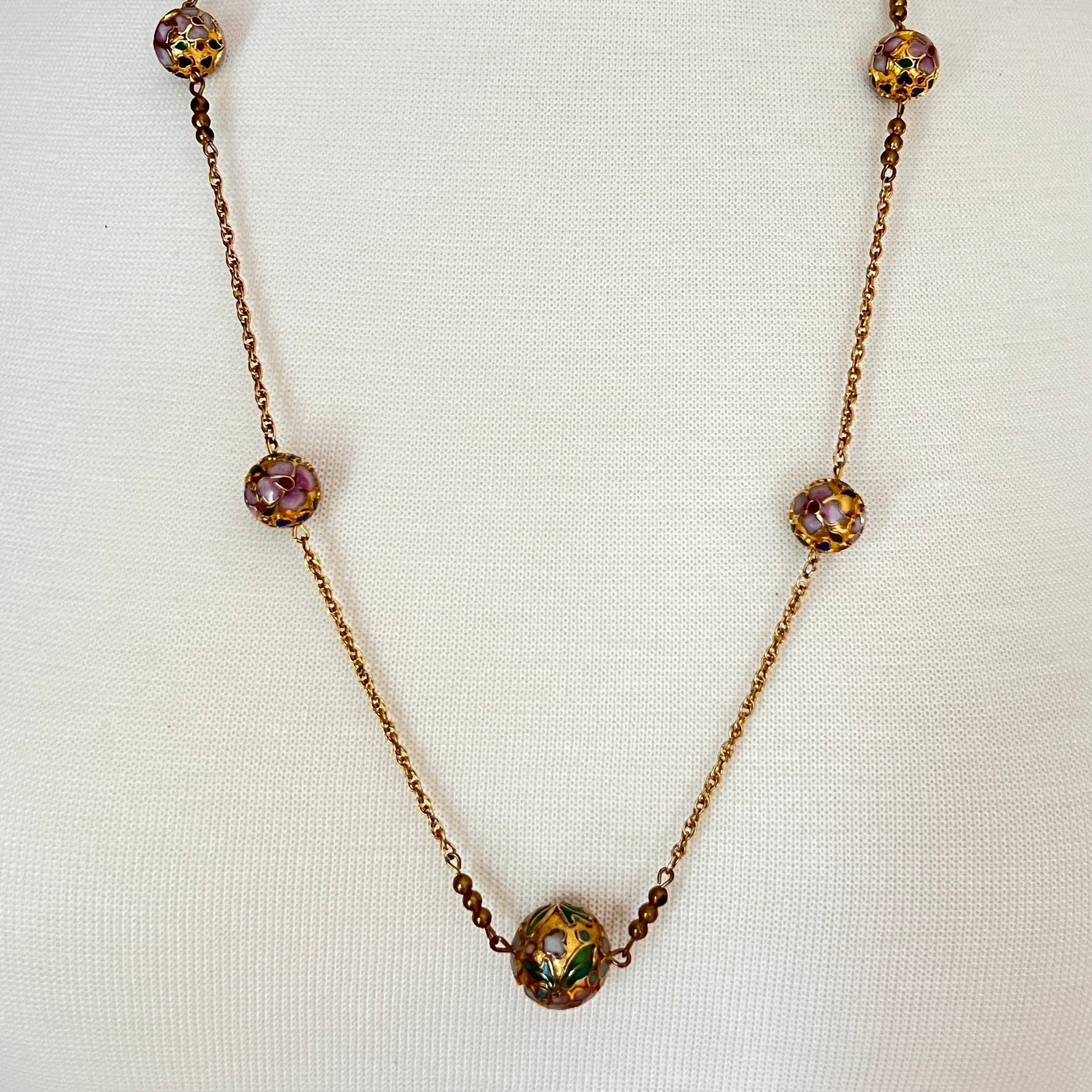 Close-up of necklace center bead with green and white floral detail