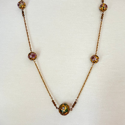 Close-up of necklace center bead with green and white floral detail