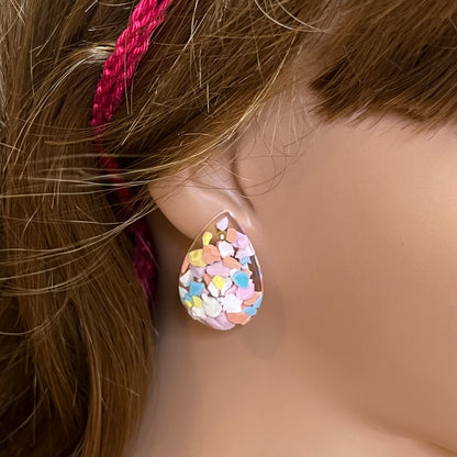 Close-up of a colorful teardrop earring on a mannequin ear.