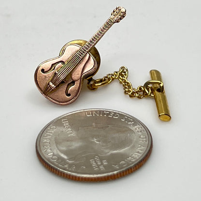 Vintage guitar tie tack next to quarter for size reference