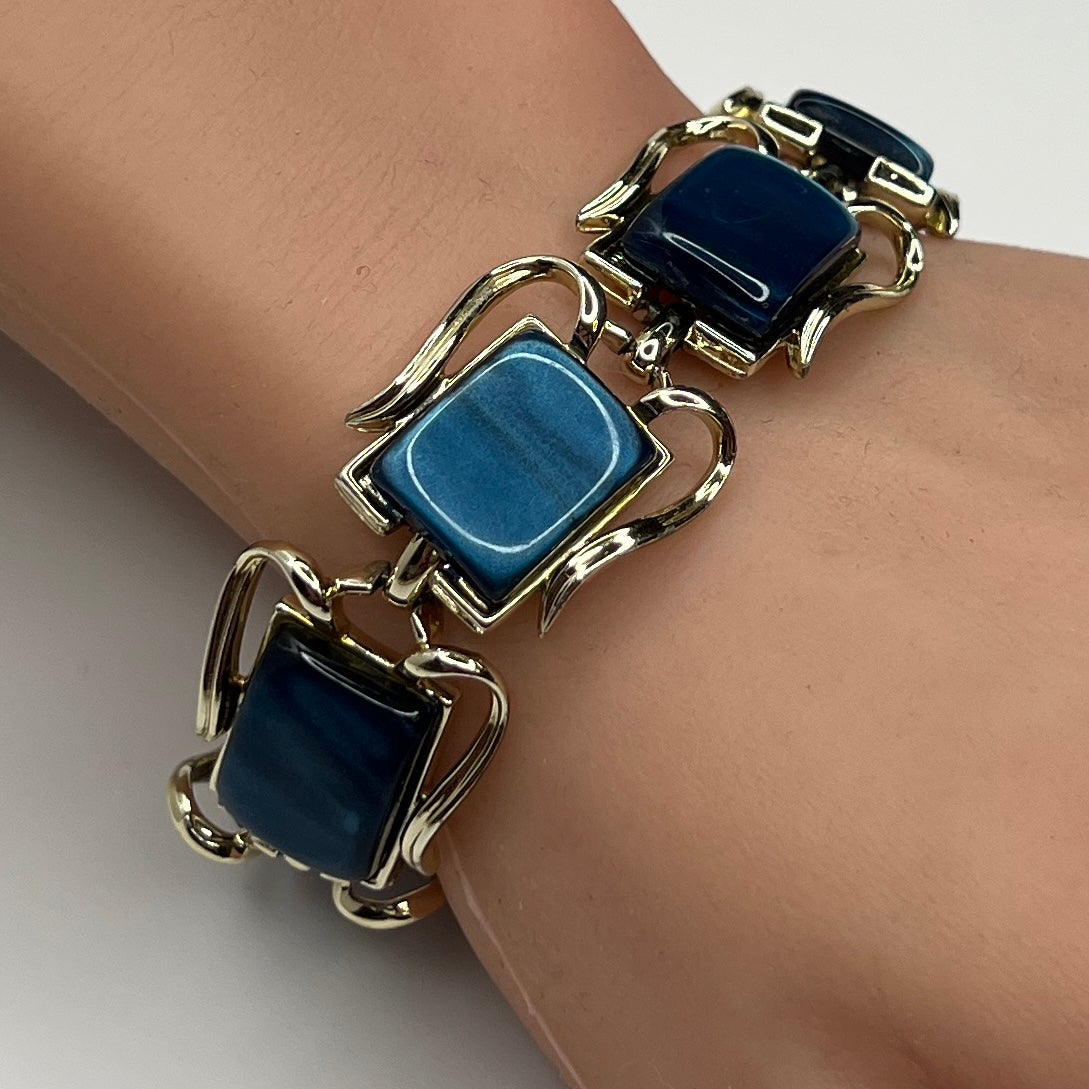 Coro blue lucite thermoset bracelet on wrist with sculptural gold-tone links