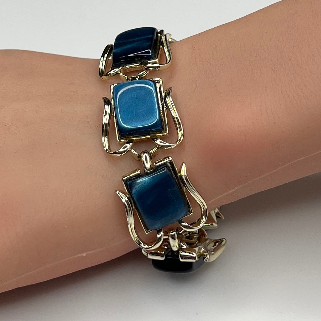 Coro blue lucite thermoset bracelet on wrist with sculptural gold-tone links