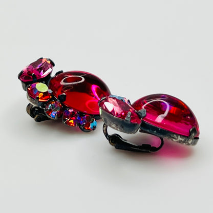 Pair of ornate earrings with pink and multicolored gemstones on a light gray background