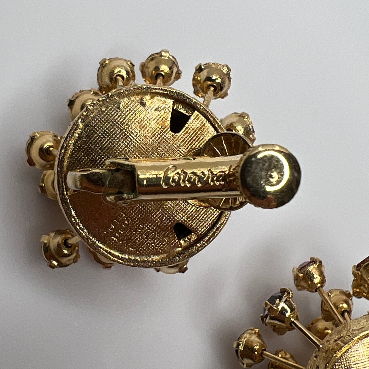 Matching Corocraft clip-on earrings with radiating rhinestone design in pink and plum tones