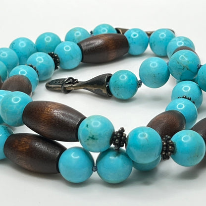 Close-up of EXEX tag and sterling hook clasp with turquoise and wood bead detail