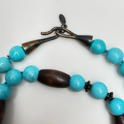 Close-up of EXEX tag and sterling hook clasp with turquoise and wood bead detail