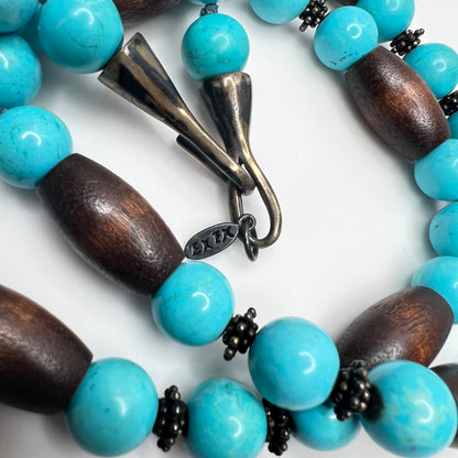 Close-up of EXEX tag and sterling hook clasp with turquoise and wood bead detail