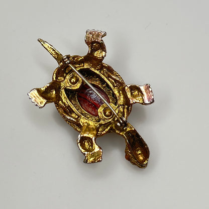 Close-up of turtle brooch with yellow rhinestones and detailed gold filigree