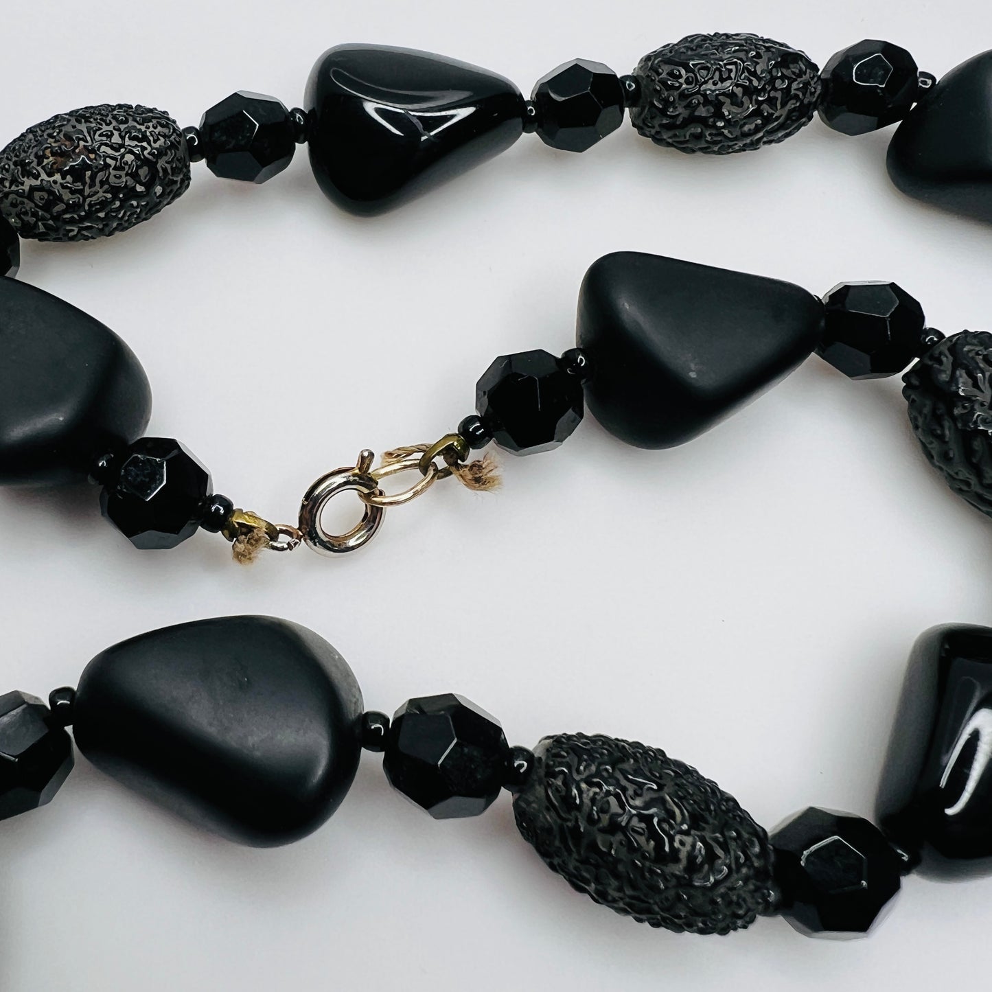 Detail of silver-tone spring ring clasp on black glass necklace