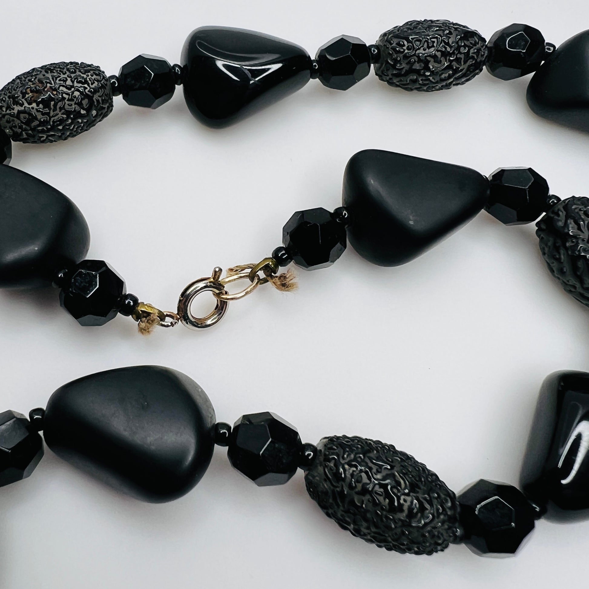 Detail of silver-tone spring ring clasp on black glass necklace