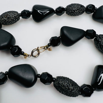 Detail of silver-tone spring ring clasp on black glass necklace