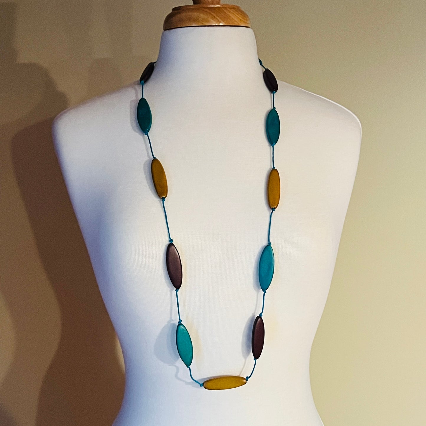 Necklace with multicolored oval beads on a mannequin against a neutral background