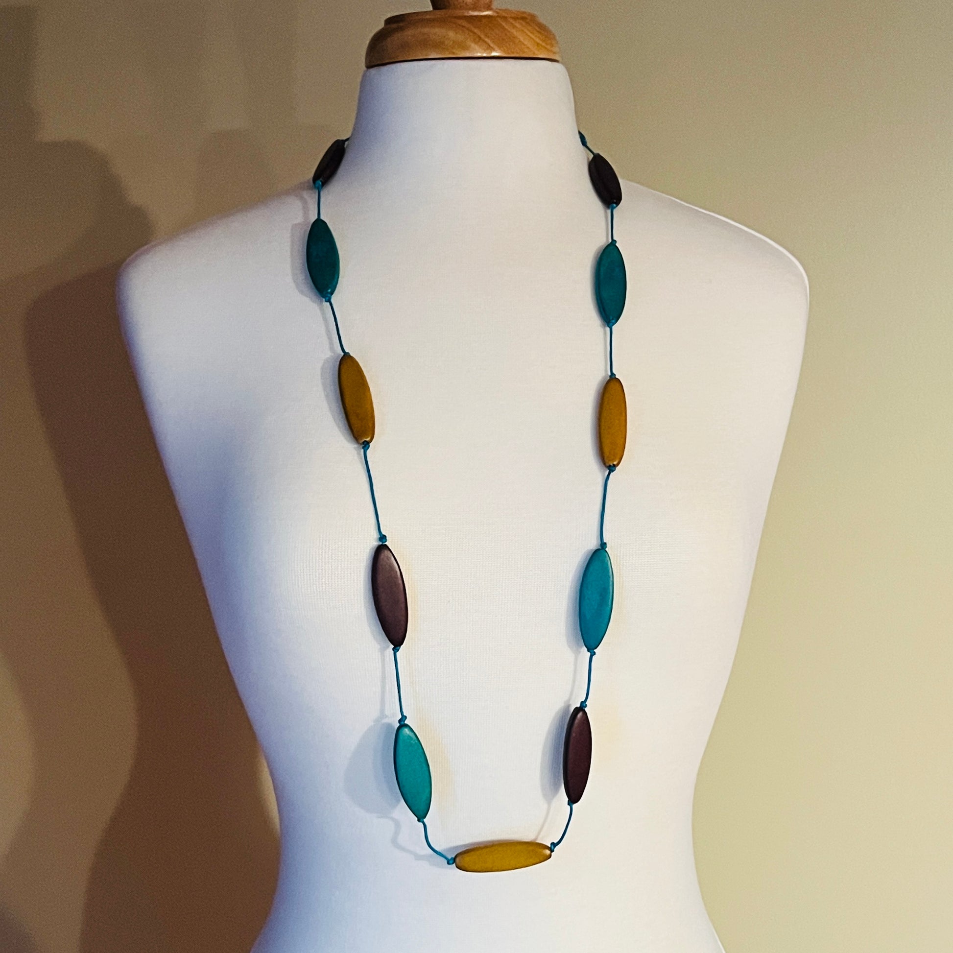 Necklace with multicolored oval beads on a mannequin against a neutral background