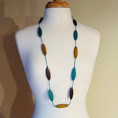 Necklace with multicolored oval beads on a mannequin against a neutral background