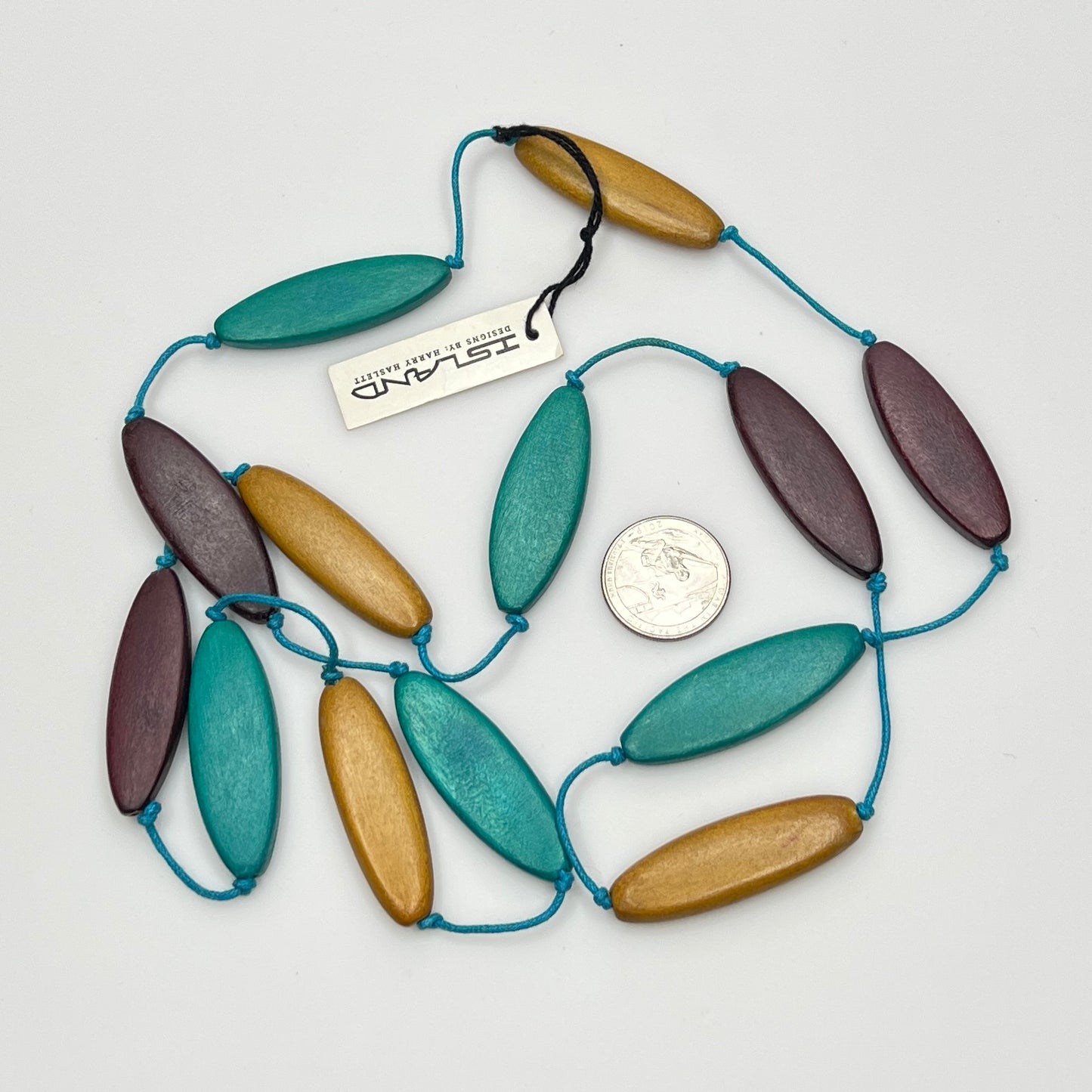 Necklace with wooden beads and blue string, size comparison with a coin, on a white background