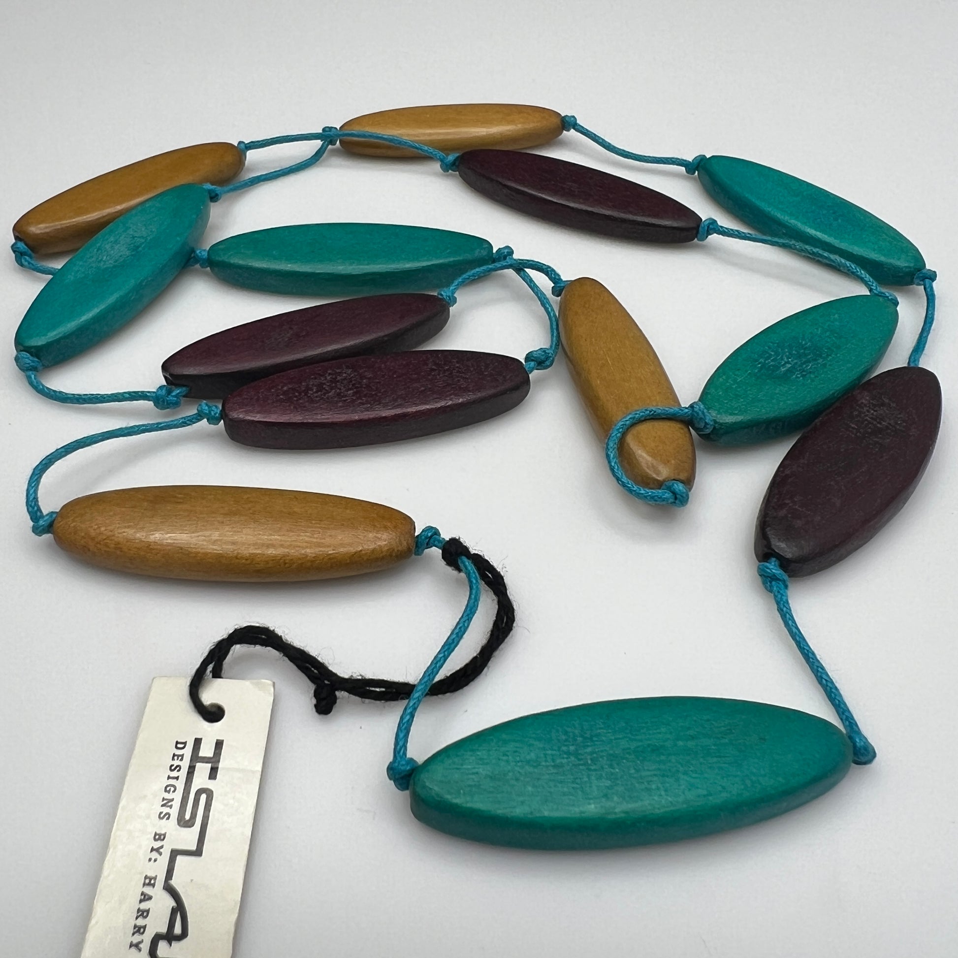 Harry Haslett Island Design necklace with long oval wood beads in teal, plum, and mustard on turquoise cord.