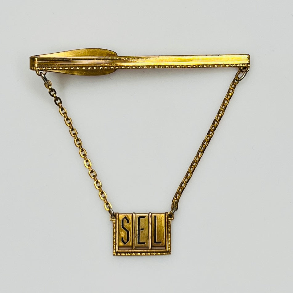Full view of midcentury monogram tie clip in gold-tone brass