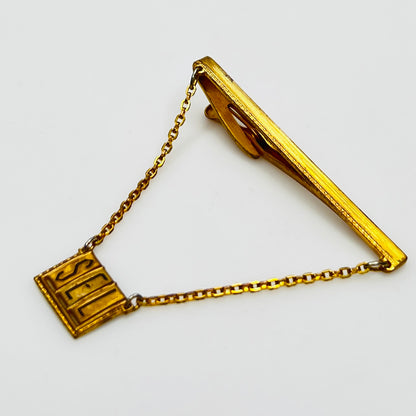 Side view of midcentury monogram tie clip in gold-tone brass