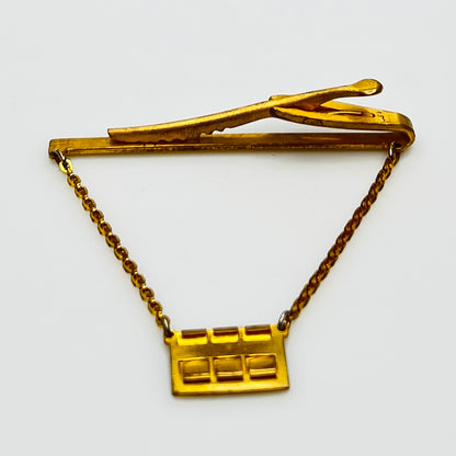 Side view of midcentury monogram tie clip in gold-tone brass