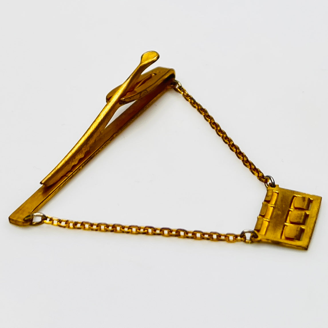 Side view of midcentury monogram tie clip in gold-tone brass