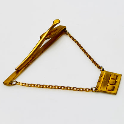 Side view of midcentury monogram tie clip in gold-tone brass