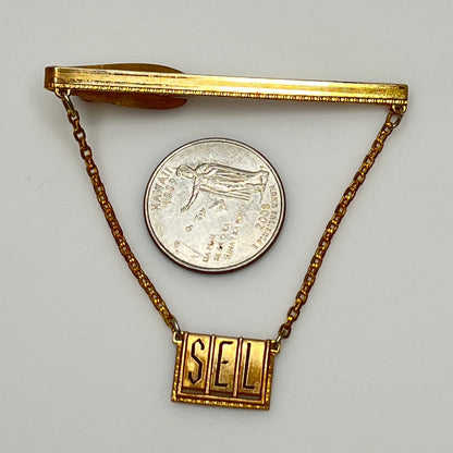 Vintage brass tie bar with "SEL" monogram and chain guard, 1950s