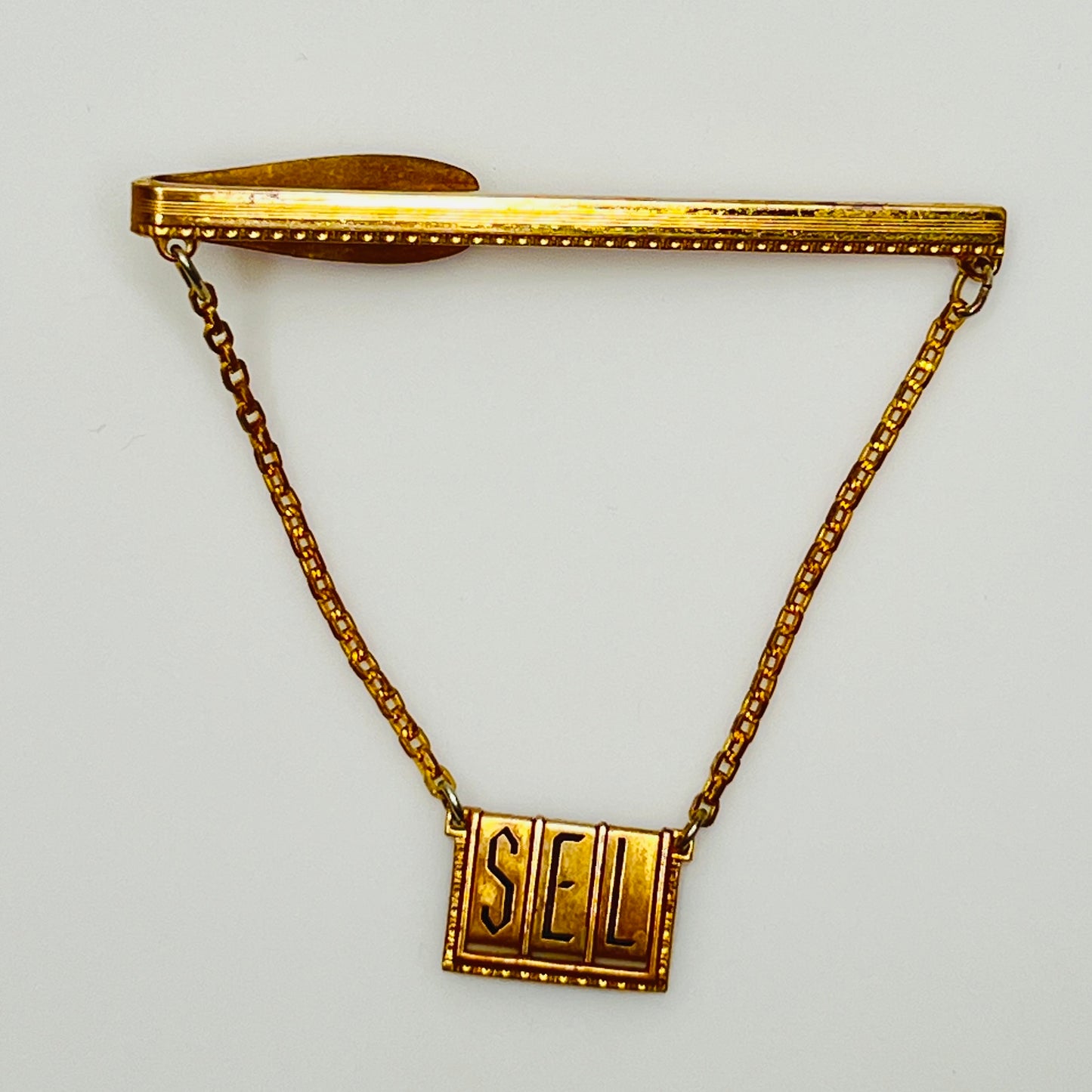 Close-up of engraved initials "SEL" on brass tile