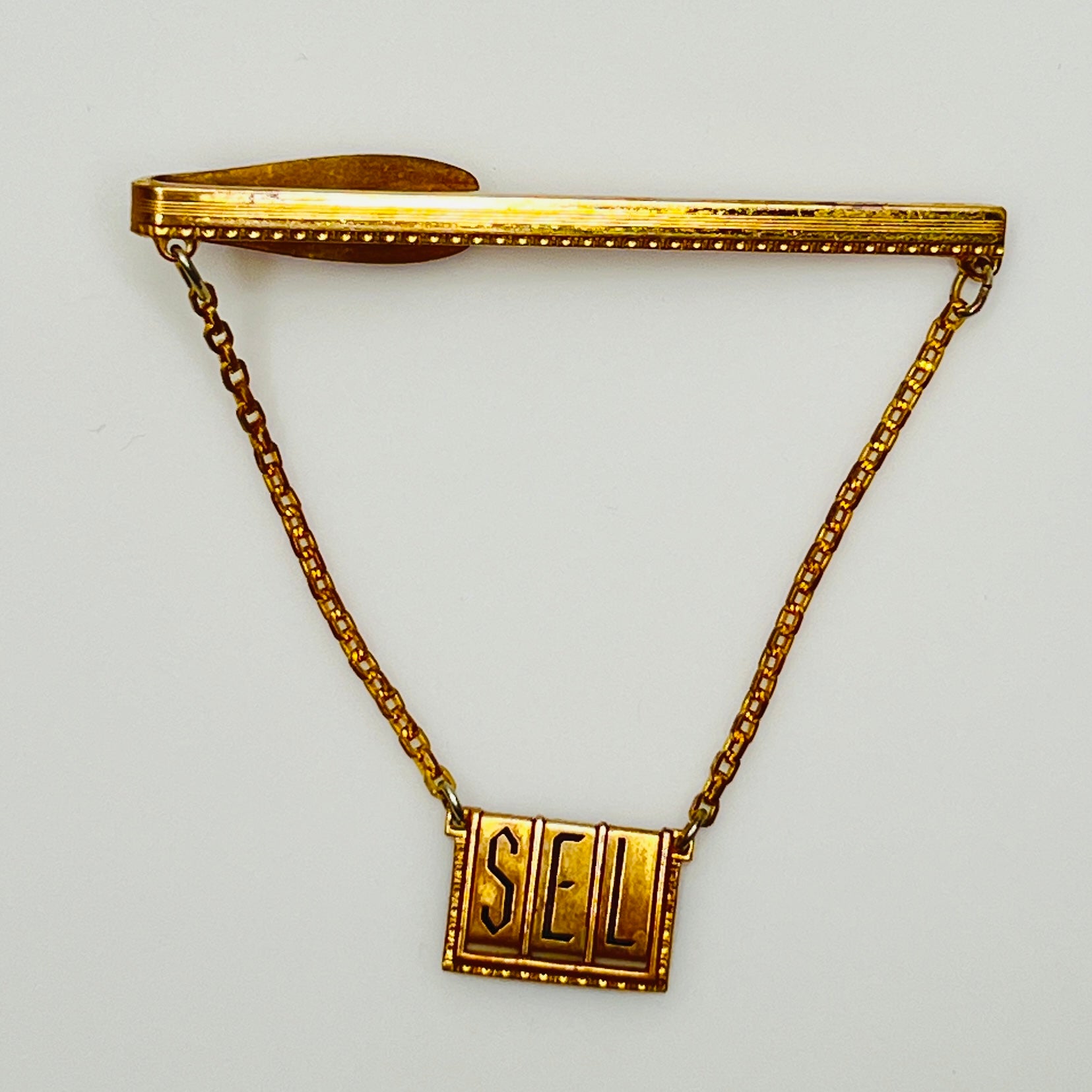 Close-up of engraved initials "SEL" on brass tile