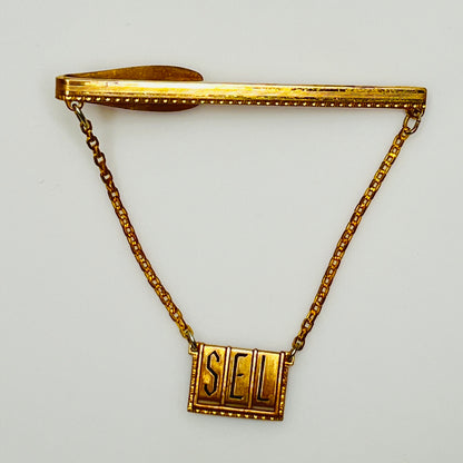 Close-up of engraved initials "SEL" on brass tile