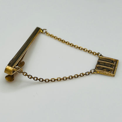 Vintage brass tie bar with "SEL" monogram and chain guard, 1950s
