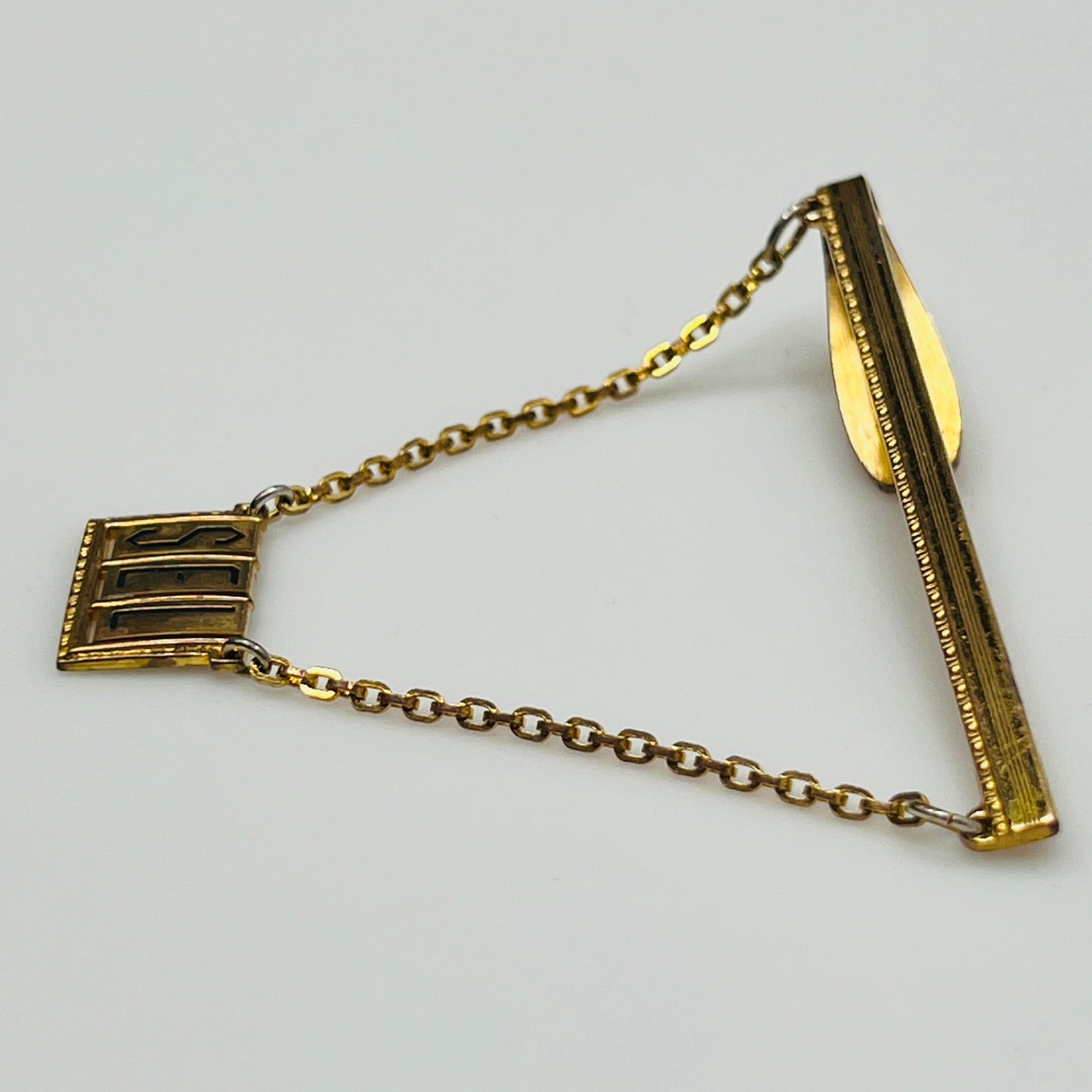 Vintage brass tie bar with "SEL" monogram and chain guard, 1950s