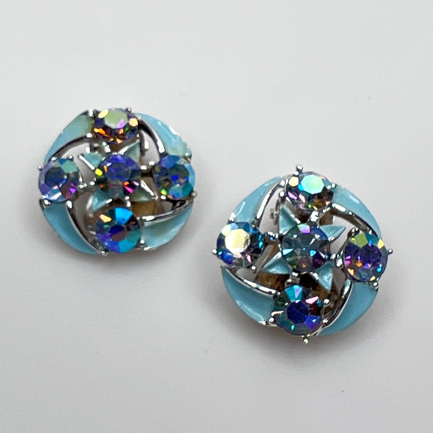 Close-up of round rhinestone earrings with blue enamel petals