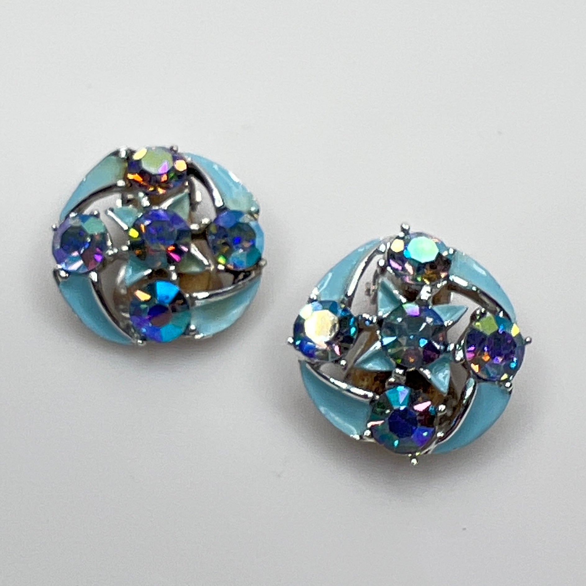Close-up of round rhinestone earrings with blue enamel petals