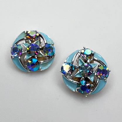 Close-up of round rhinestone earrings with blue enamel petals