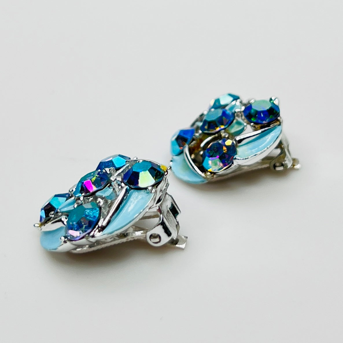 Close-up of round rhinestone earrings with blue enamel petals