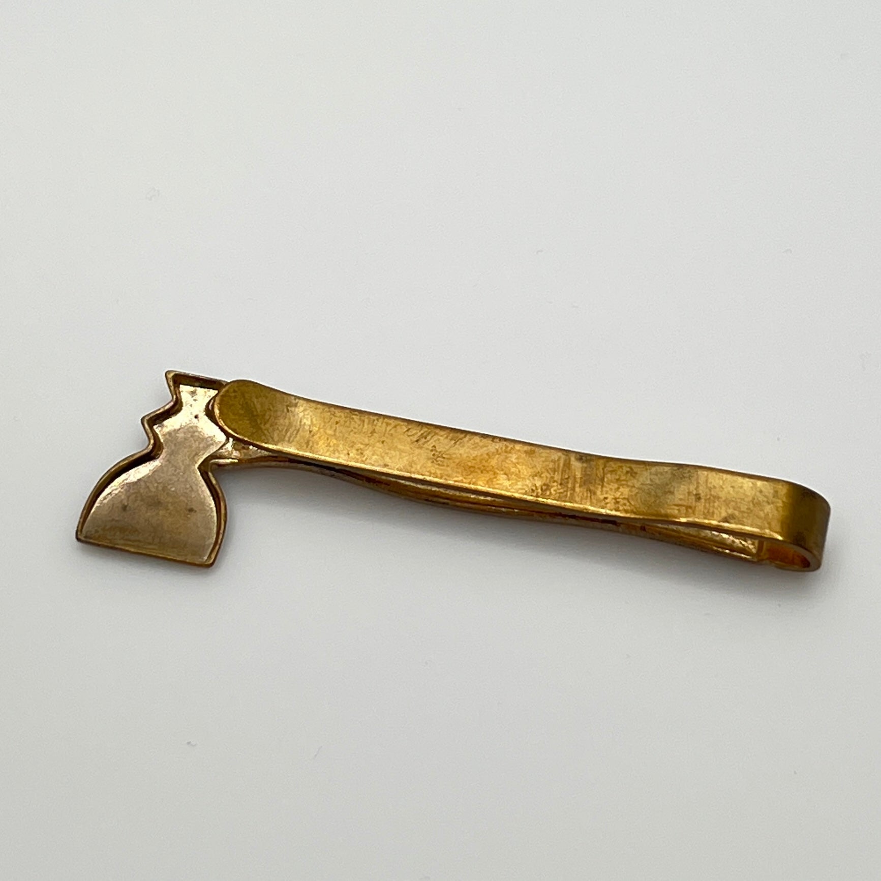 Close-up of novelty axe-shaped tie clip, mid-century brass finish