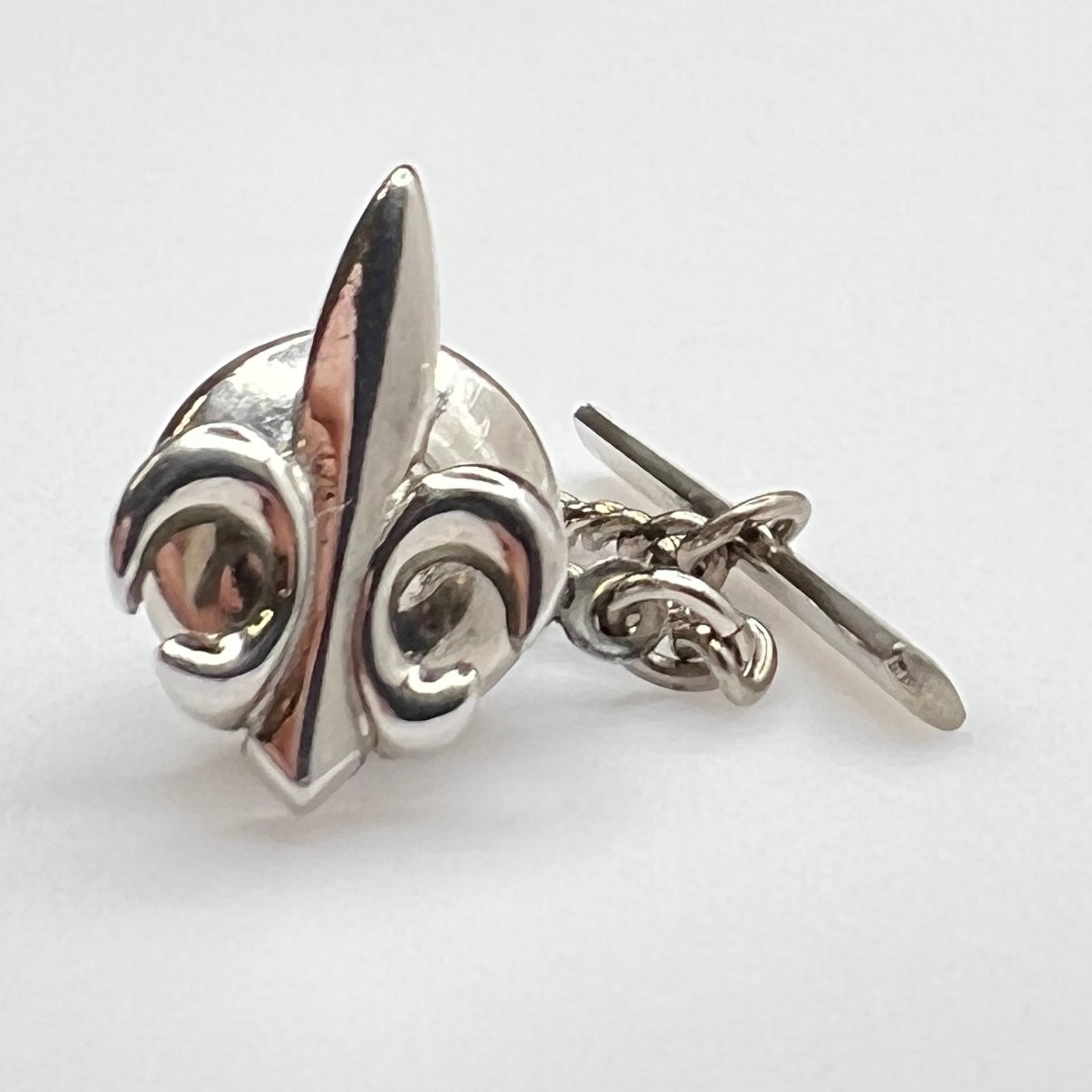 Silver fleur-de-lis tie clip on a white background