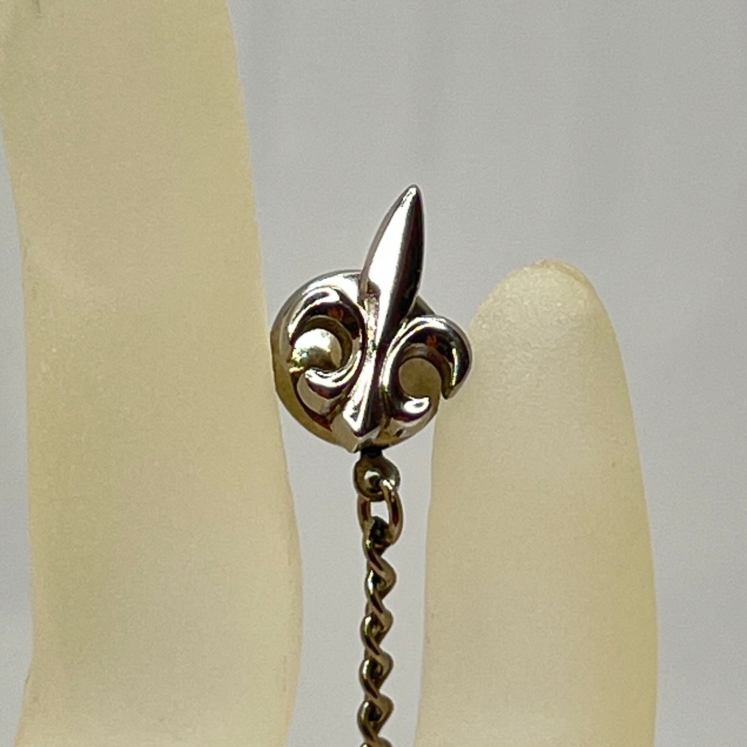 Vintage silver fleur-de-lis tie tack with chain and clutch backing.