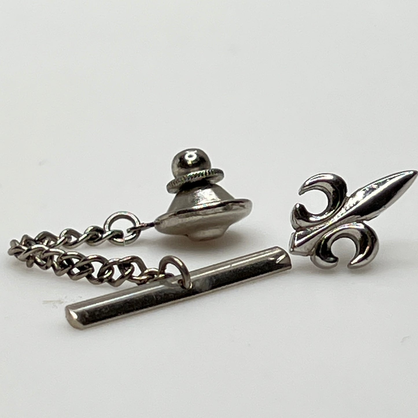 Vintage silver fleur-de-lis tie tack with chain and clutch backing.