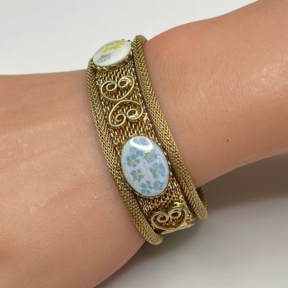 Gold mesh bracelet with hand-painted floral cabochons worn on wrist