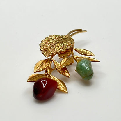 Close-up of jade cabochon rose bud floral brooch with textured gold leaves