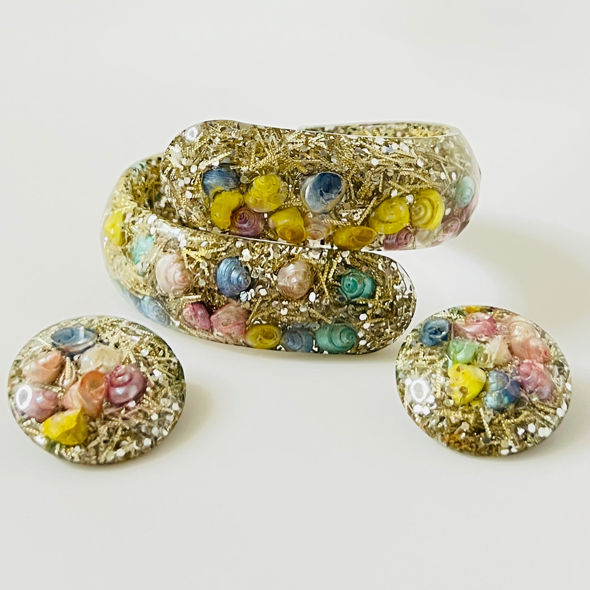 Vintage hinged bracelet and earrings with colorful shells suspended in clear lucite