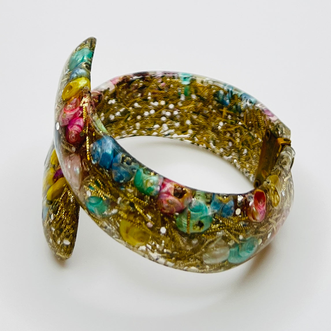 Vintage hinged bracelet with colorful shells suspended in clear lucite